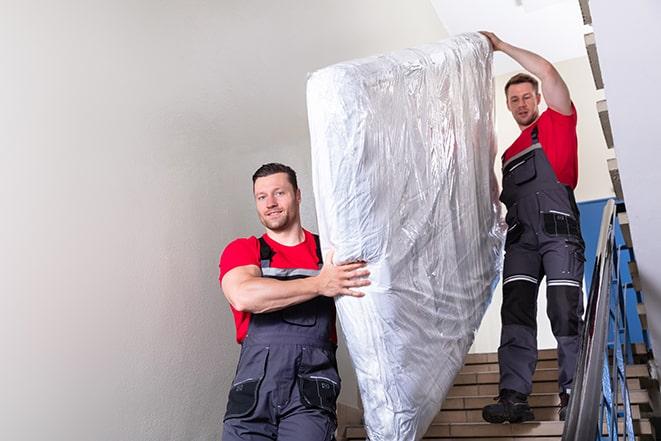 two workers lifting a box spring out of a bedroom in Lancaster, NY